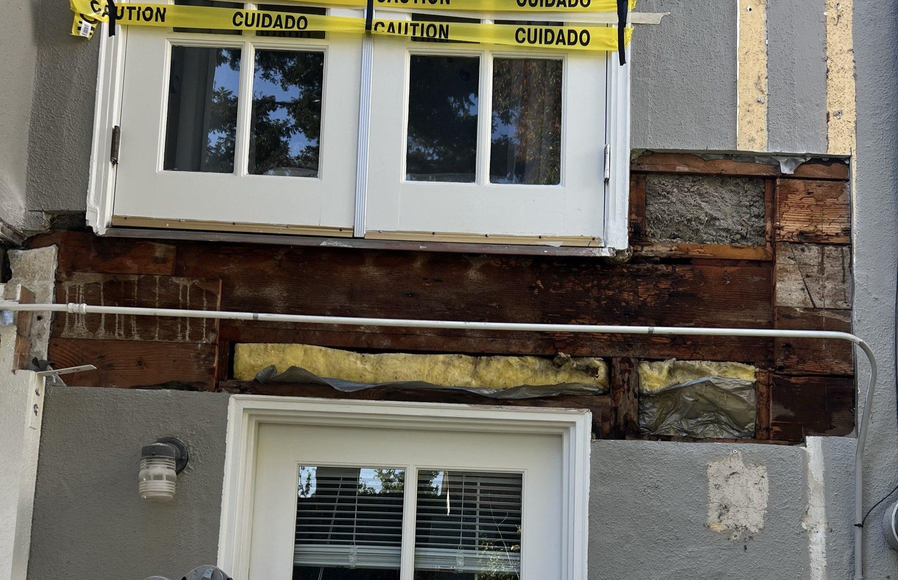 Bay window header beam fully rotted and exposed during stucco demolition — full extent of structural water damage visible across the wall