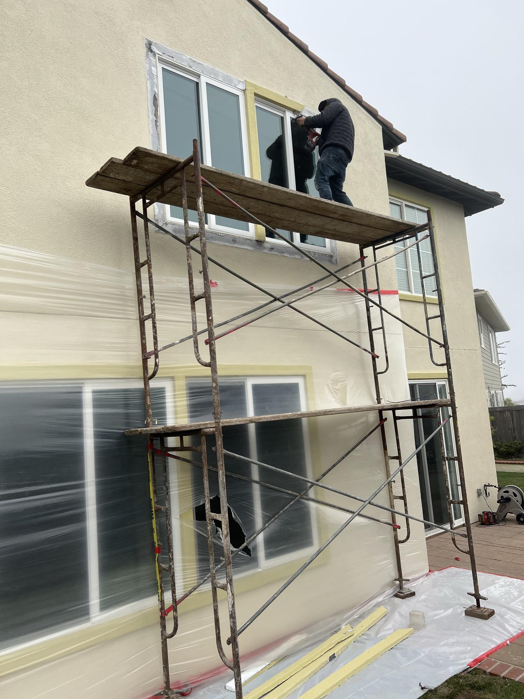 Gadget Construction crew on scaffolding performing stucco work on a Bay Area home — full window masking, plastic containment, professional setup for three-coat application