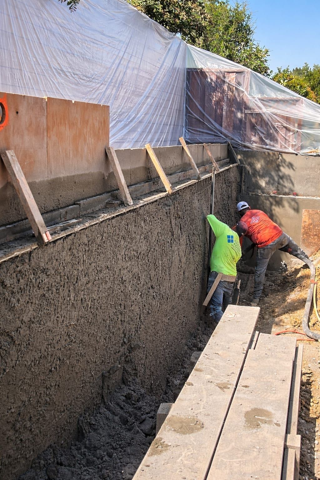 Gadget Construction crew applying stucco finish to a new retaining wall on a Bay Area hillside job site
